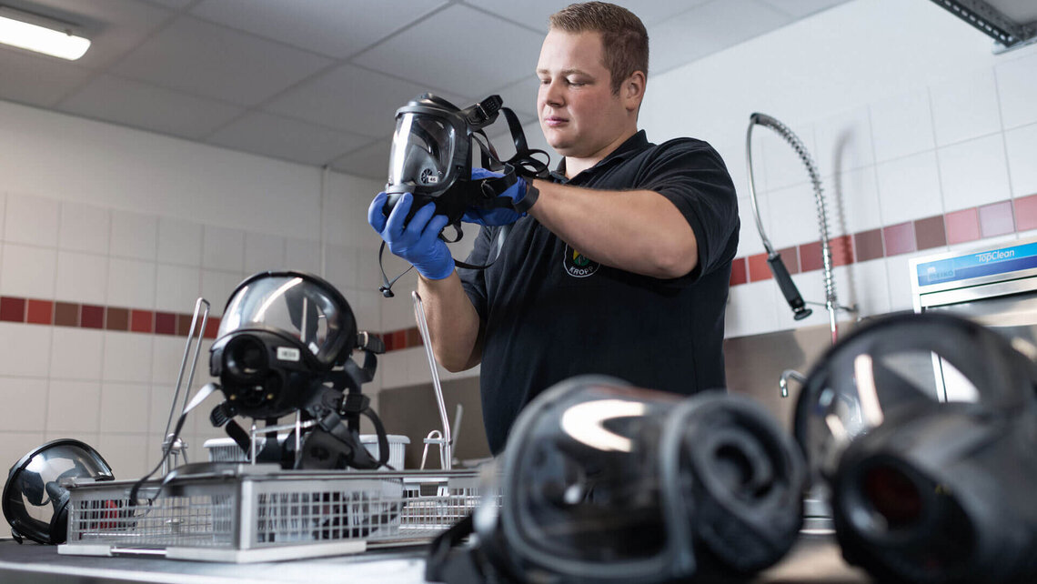 Atemschutzgerätewart bestückt Korb mit Atemschutzmasken zur Reinigung im TopClean M von Meiko  Atemschutzgerätewart bestückt Korb mit Atemschutzmasken zur Reinigung im TopClean M von Meiko
