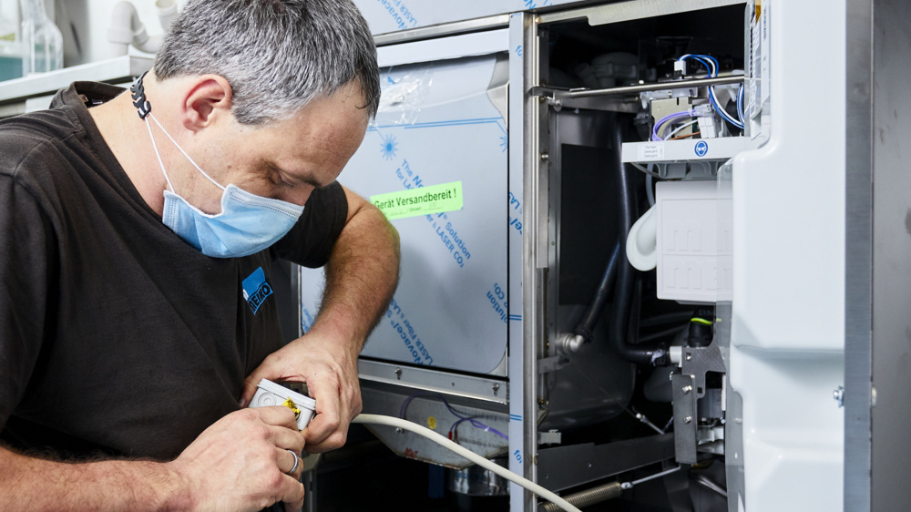 Technicien installant un lave-vaisselle professionnel frontal MEIKO en cuisine de restaurant