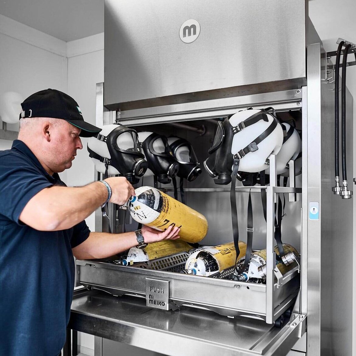 A RPE technician loads the TopClean D pre-cleaning washer with masks and compressed air bottles A RPE technician loads the TopClean D pre-cleaning washer with masks and compressed air bottles