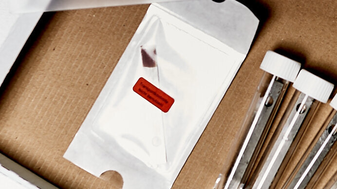 Einen von sechs Bioindikatoren als Transportkontrolle ungeöffnet in die Transportbox zurückgeben.